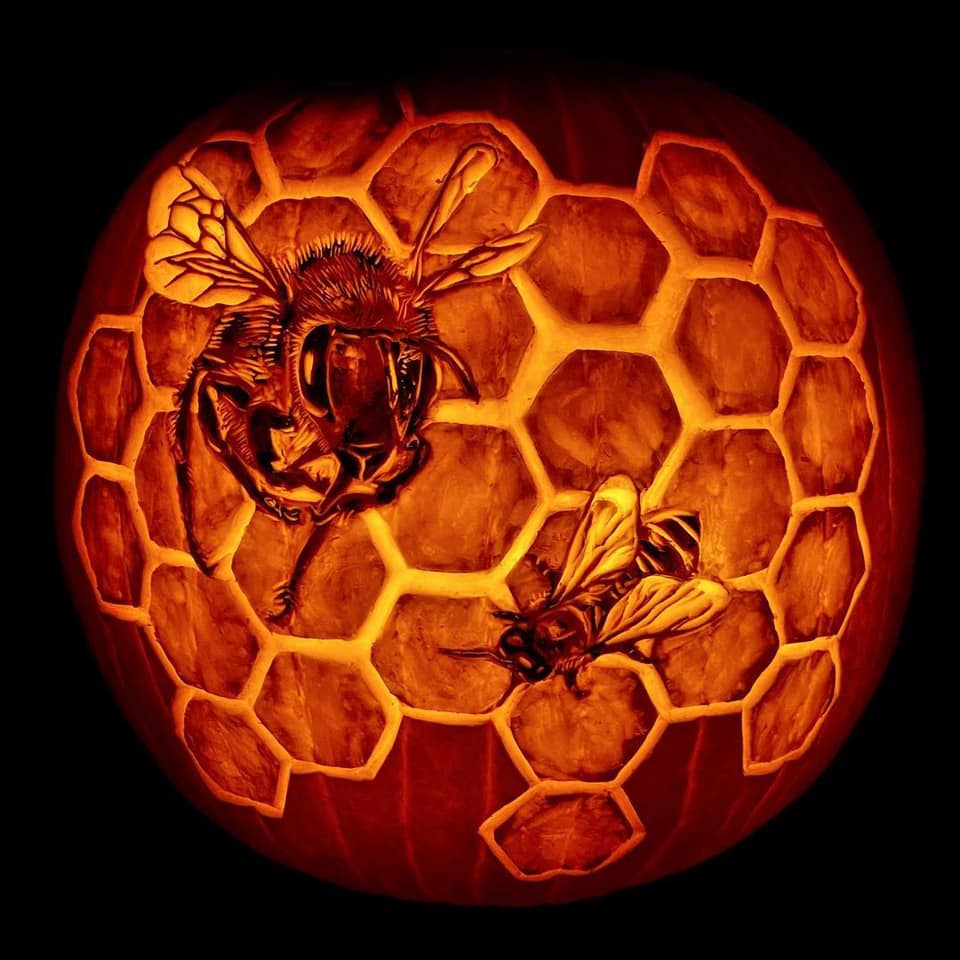 Carved pumpkin with honeybee and honeycomb design for a pollinator-friendly Halloween garden